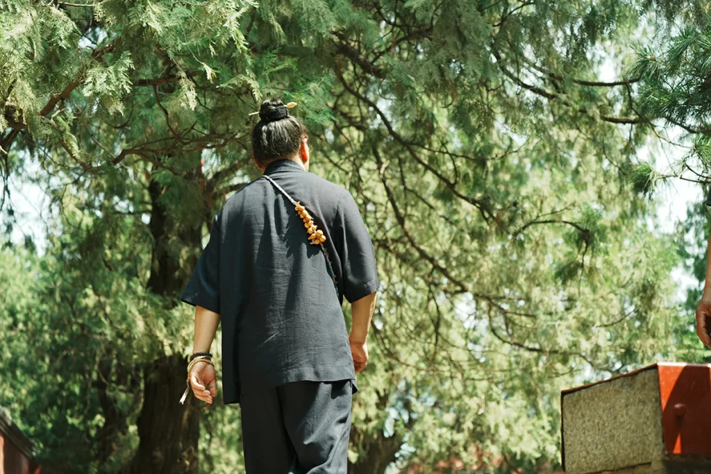 Visitor walking through green Taoist temple garden