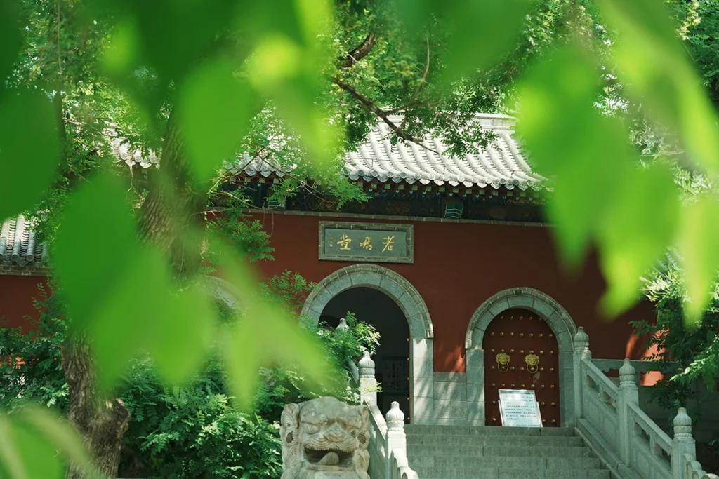 Traditional red temple entrance framed by green leaves