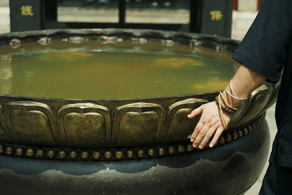 Hands near Taoist ritual water vessel for ceremony preparation