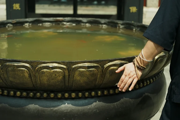 Hands near Taoist ritual water vessel for ceremony preparation