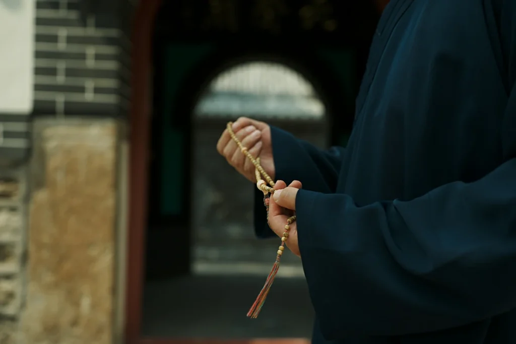 Hands holding prayer beads in Taoist temple doorway